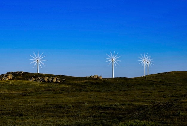 A vast solar panel farm under a clear blue sky, with wind turbines spinning in the distance. The landscape is clean and modern, symbolizing sustainable energy production.