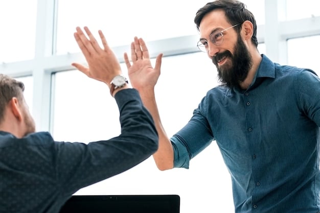 A close-up shot of two startup team members high-fiving in celebration of a successful project completion. The background shows blurred office activity, symbolizing teamwork and achievement.