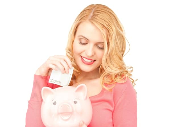 A person happily putting money into a piggy bank, symbolizing saving and achieving financial goals.