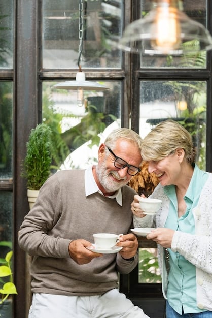 An image featuring a cheerful older couple sitting on a porch swing, looking out over a scenic landscape. They are both holding cups of coffee, and the atmosphere is relaxed and peaceful.