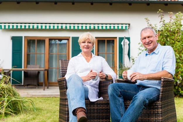 Two seniors sitting on a porch swing, smiling and looking relaxed, with a lush green lawn and a comfortable-looking house in the background, representing a happy and secure retirement.